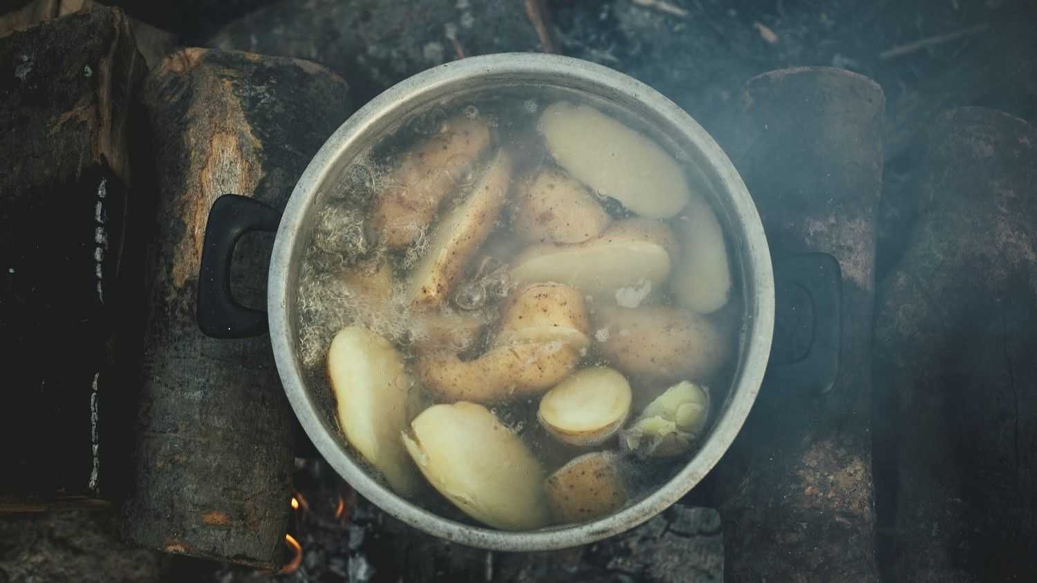 Boiling Potatoes in a pot on a wooden fireplace in Idomeni